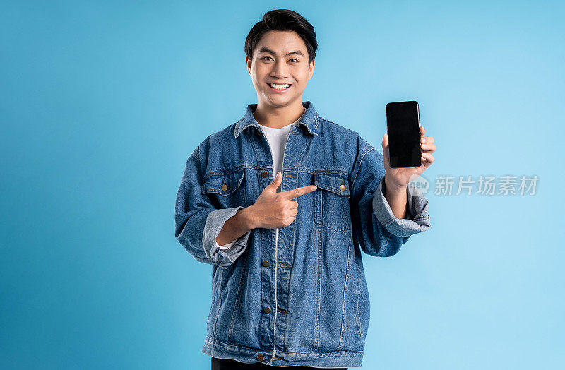 年轻的亚洲男子在蓝色背景上使用电话