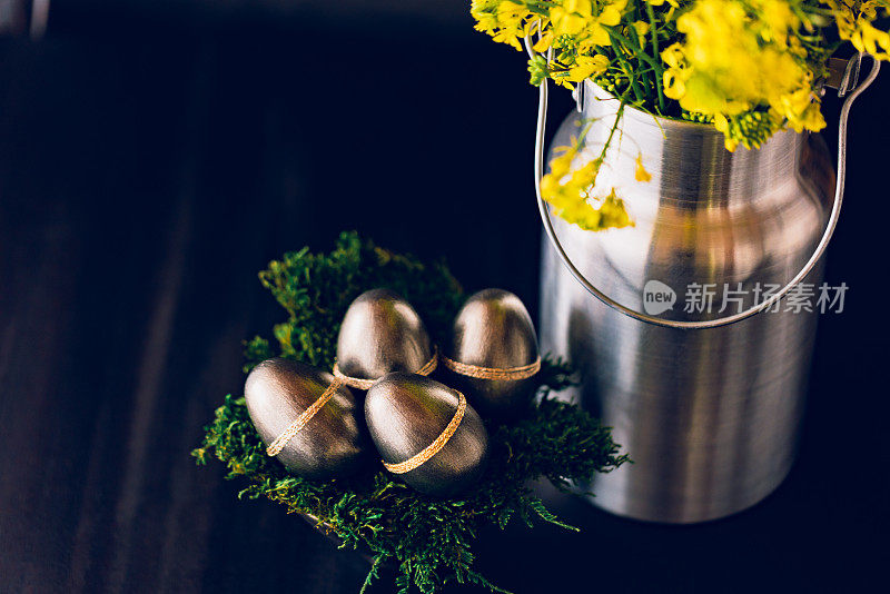 黑色低调的静物，金属色的复活节彩蛋和银色的牛奶罐，花瓶与油菜花束