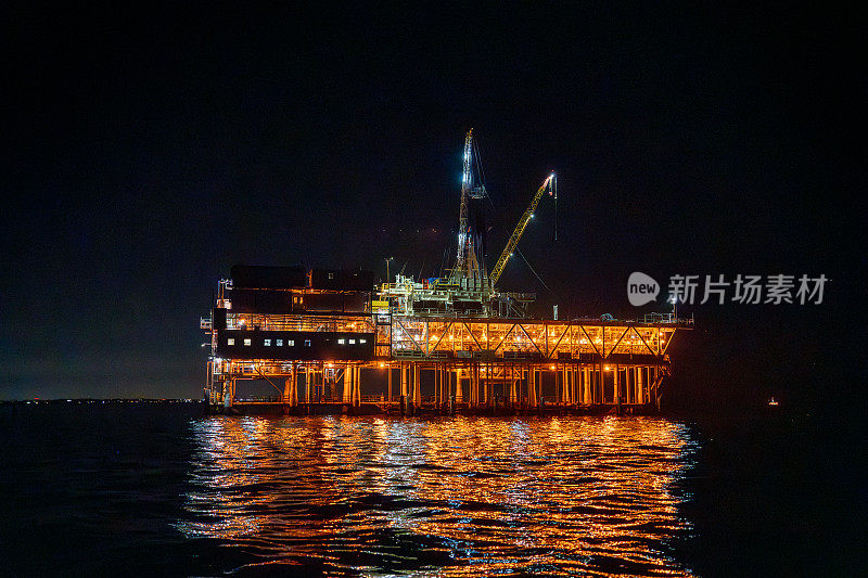 夜晚，洛杉矶海岸外，埃斯特平台矗立在太平洋上，灯火通明，水力压裂钻机在那里工作，从海底深处开采天然气。