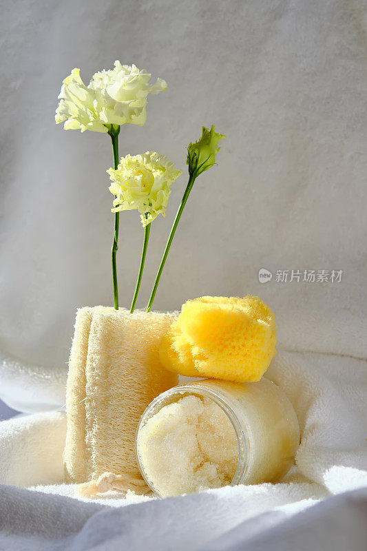 搓澡，丝瓜毛巾和有机海绵的背景上的毛巾形浴巾与鲜花。