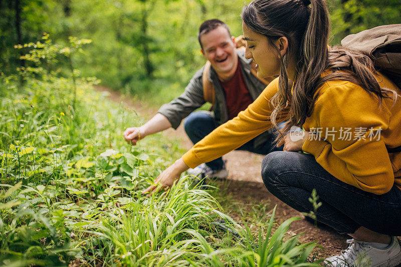 两个朋友，一个年轻的女人和一个患有唐氏综合症的男人，一起在森林里远足