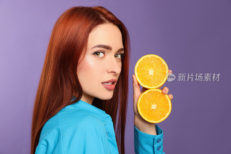 美丽的女人，染成红色的头发，紫色的背景上有橘子
