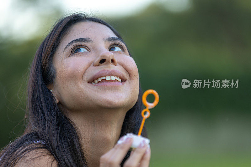 年轻女子正在外面吹泡泡。