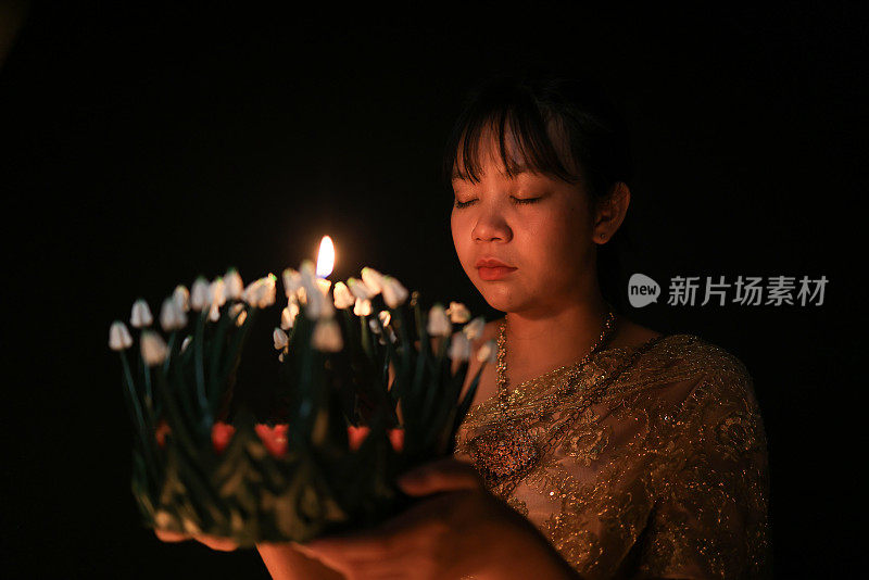 一位可爱的年轻女子穿着泰国传统服装，手拿“克拉通”向水神祈祷