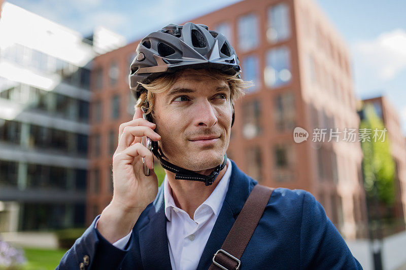 帅哥骑着自行车在城市里穿梭，用智能手机打电话。在漫长的工作日后骑自行车下班的男性城市通勤者。