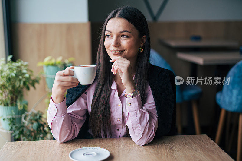 漂亮时尚的女孩坐在咖啡馆里喝咖啡