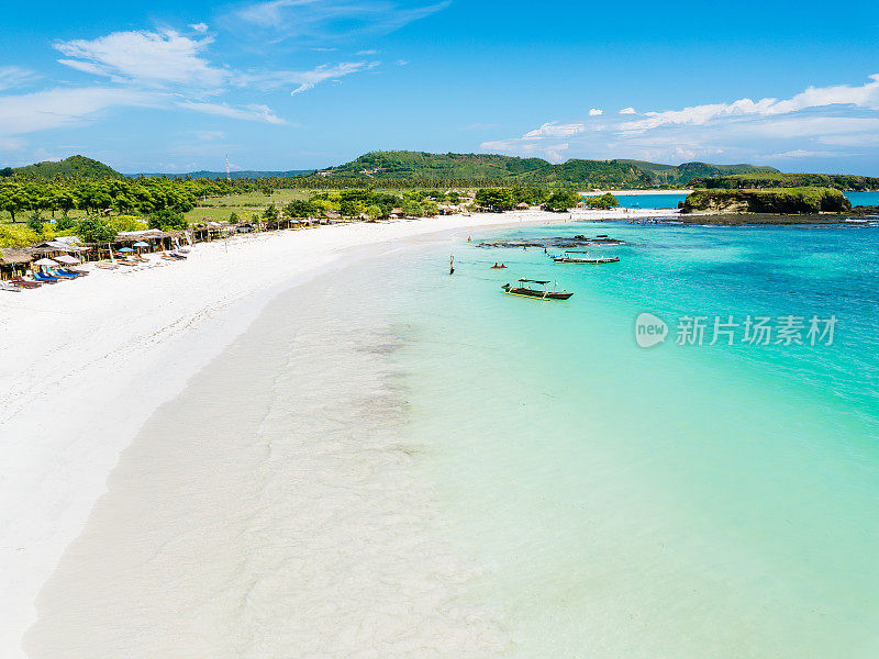 龙目岛宁静的热带海滩鸟瞰图，清澈的海水，郁郁葱葱的绿色植物，和附近停泊的船只。