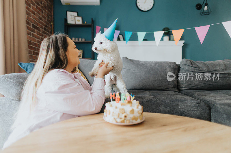 快乐的年轻女子在家里为她的狗庆祝生日