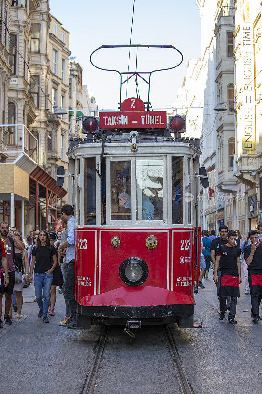 土耳其伊斯坦布尔市中心，塔克西姆隧道怀旧电车沿着istiklal大街和istiklal大街上的人群行驶