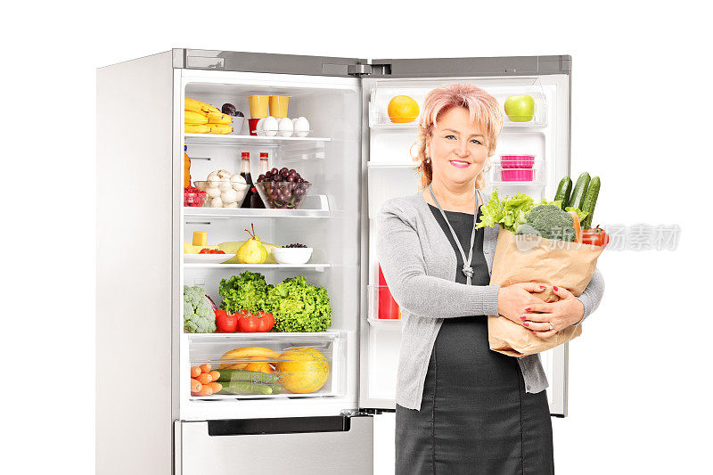 冰箱前放着蔬菜的女人