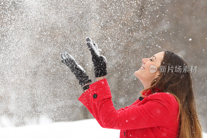 穿红衣服的女人在冬天向空中扔雪
