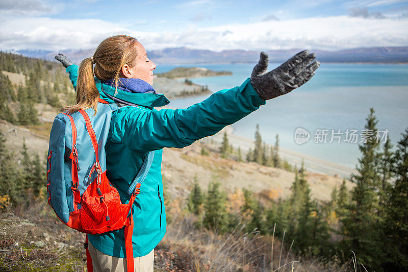 欢呼的女性徒步旅行者伸出手臂俯瞰湖面