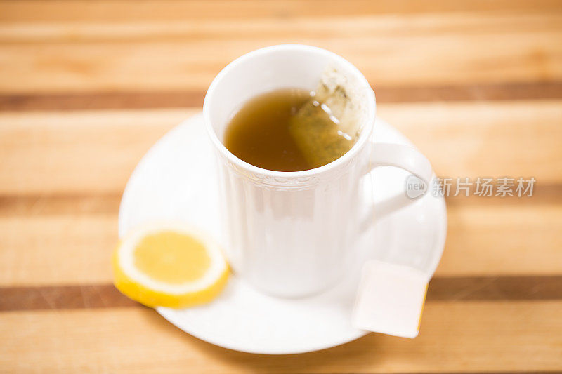 草药茶，白色杯子加柠檬片。木制的桌子。袋泡茶。