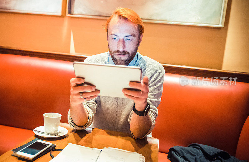 一个法国人在咖啡馆用他的数字平板电脑工作