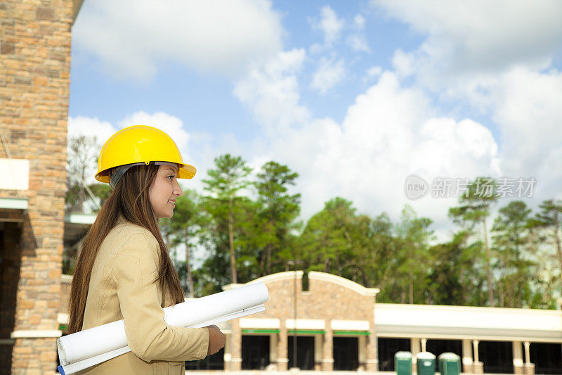 女建筑师在商业建筑工地持有计划和蓝图。