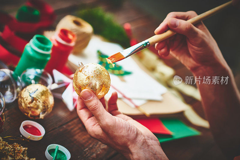 用金箔包裹圣诞装饰品的男性双手