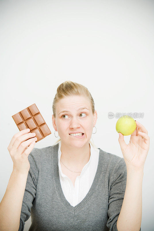 拿着巧克力和苹果的女人的饮食选择