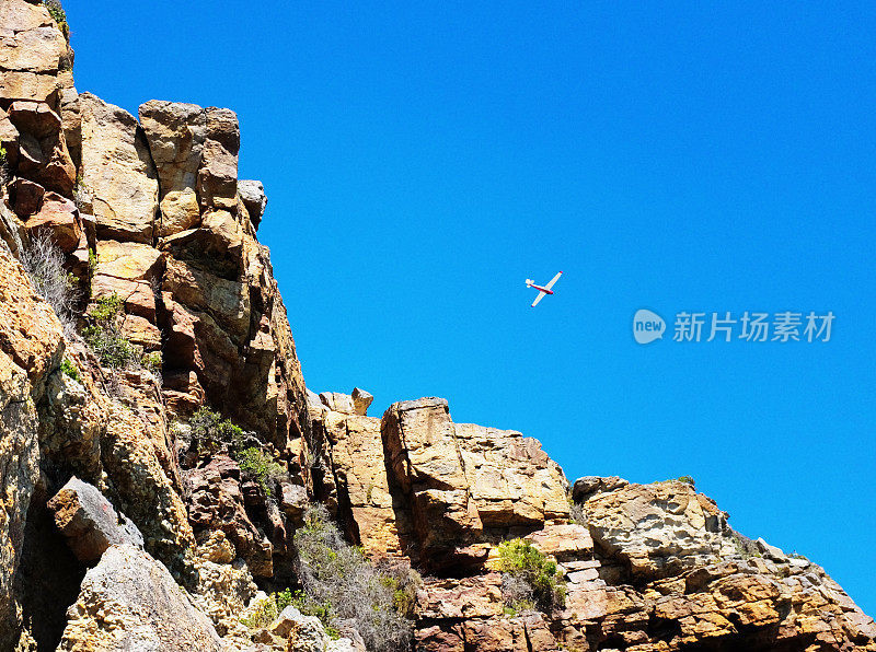 小飞机飞过岩石峭壁，从下面看