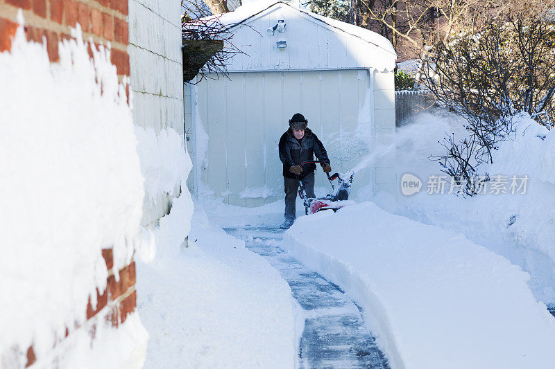 老人用吹雪机扫雪