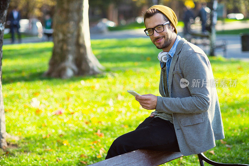 帅哥在公园玩他的智能手机