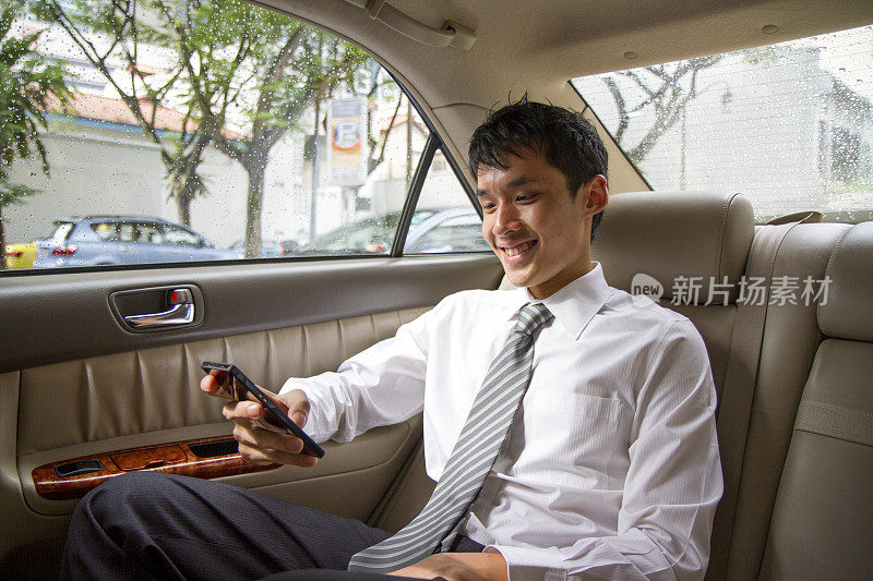 亚洲商人在车里，用手机发短信