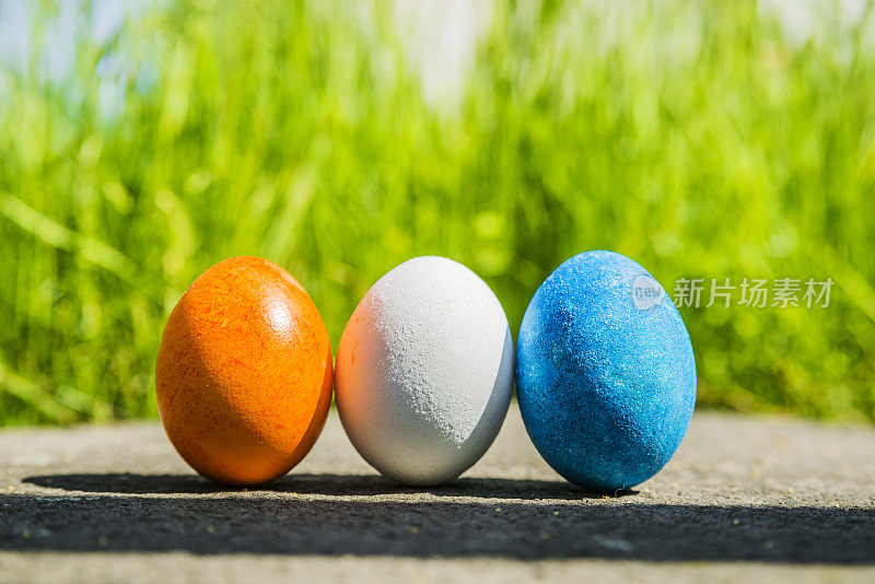 3个五彩缤纷的复活节彩蛋在草地上排成一排