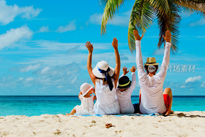 幸福的家庭和两个孩子在海滩上举手