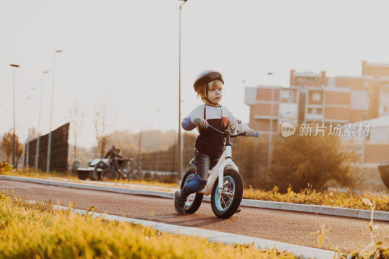 可爱的小男孩戴着安全帽骑自行车