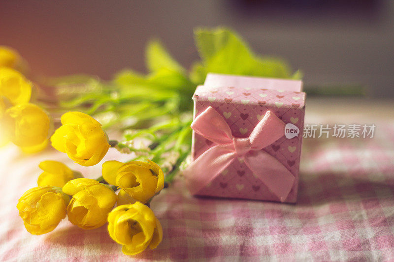 粉色背景上的礼盒和鲜花