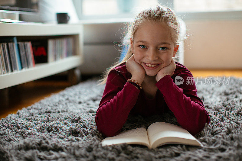美丽的年轻女孩在家里看书