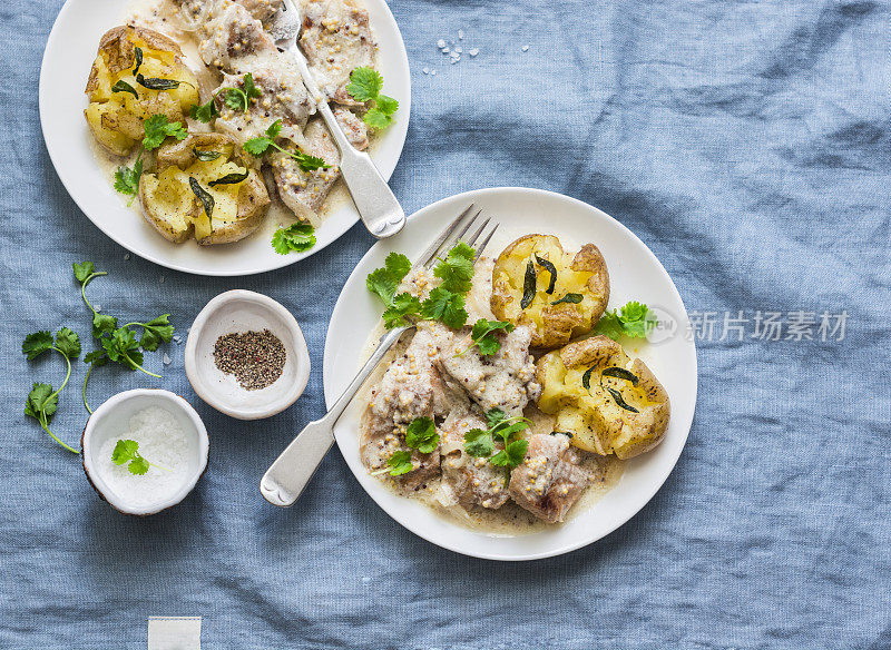 粉碎烤鼠尾草黄油土豆和芥末奶油酱肉-美味的午餐在蓝色的背景，俯视图