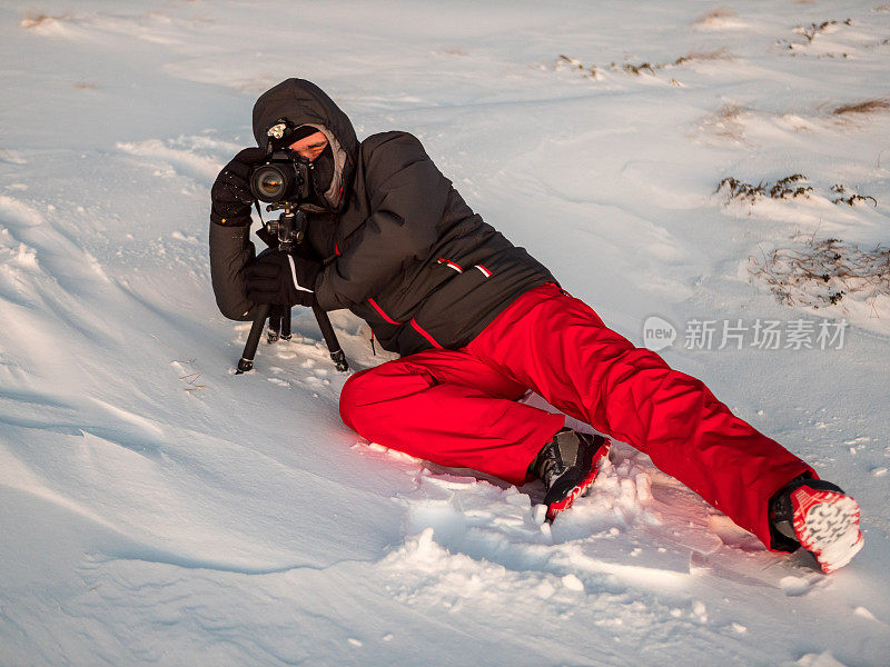 专业摄影师躺在雪地里拍摄大自然