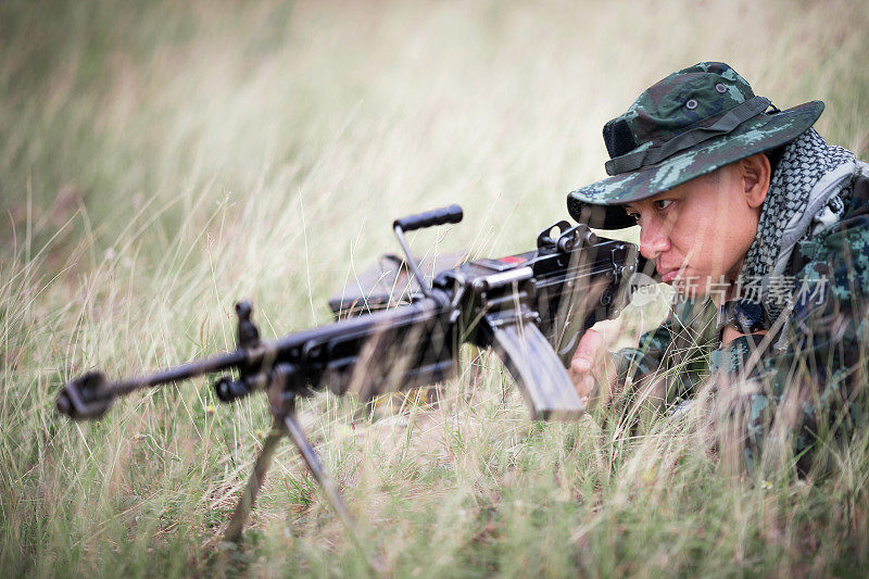 狙击手躺在草地上，用瞄准镜瞄准目标