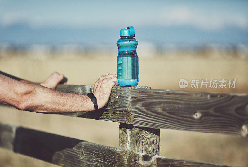 在阳光明媚的日子里，成年男性戴着健身追踪器在户外运动