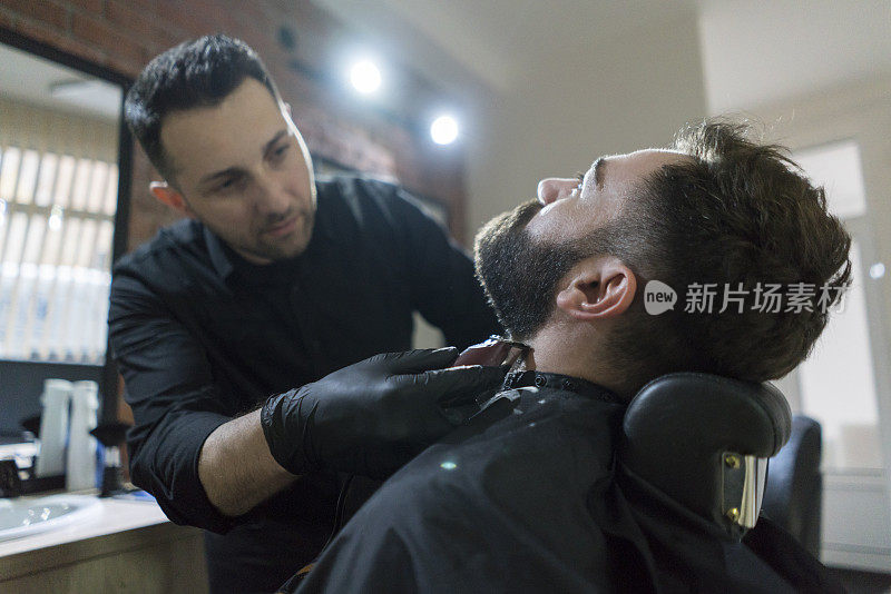一个男人正在用电动剃须刀修剪他的胡子