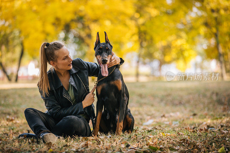 一个女人在玩她的杜宾犬