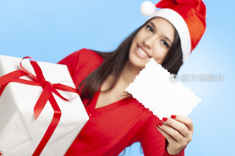 快乐的女人戴着圣诞帽拿着圣诞礼物，展示着贺卡。