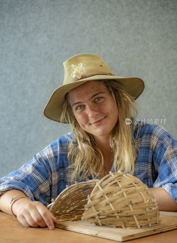 迷人的澳大利亚年轻女子微笑着她的编织竹结构。
