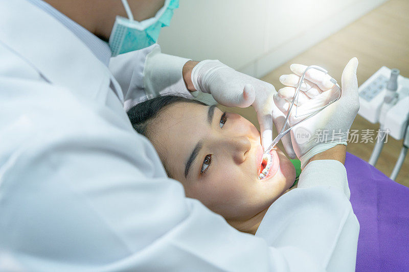 牙科医生在牙科诊所的牙医椅上检查病人的牙齿。牙科医生在他的诊所里治疗病人的牙齿。