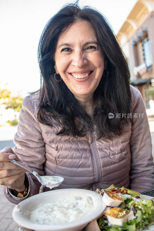 微笑的成熟女人看着镜头吃午饭