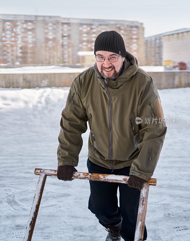 微笑的男子在院子的溜冰场除雪