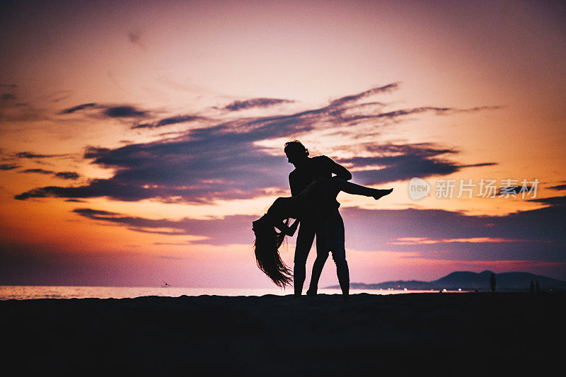 黄昏时分，一对浪漫的情侣在海滩上跳舞。