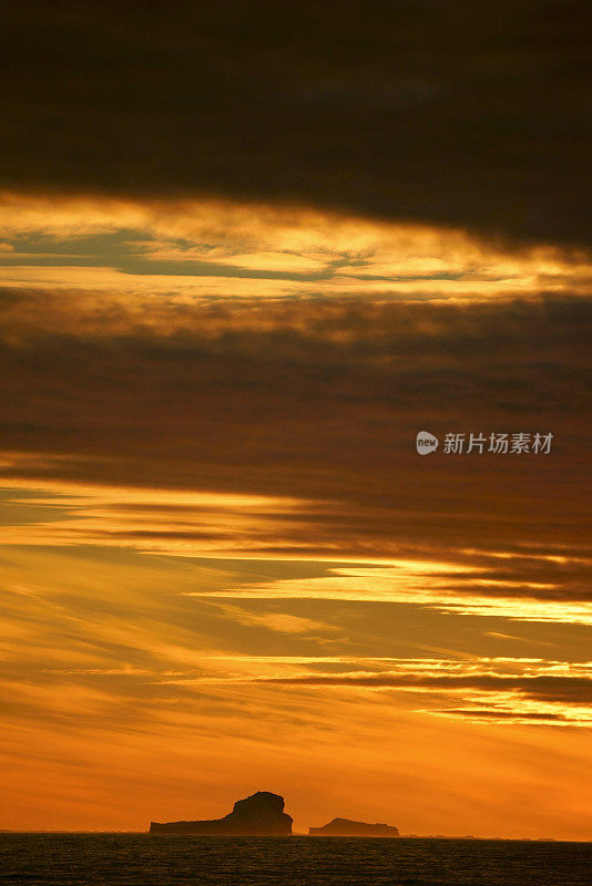 南极泻湖上的日落与漂流的冰山和雪峰的背景，勒梅尔海峡，南极洲