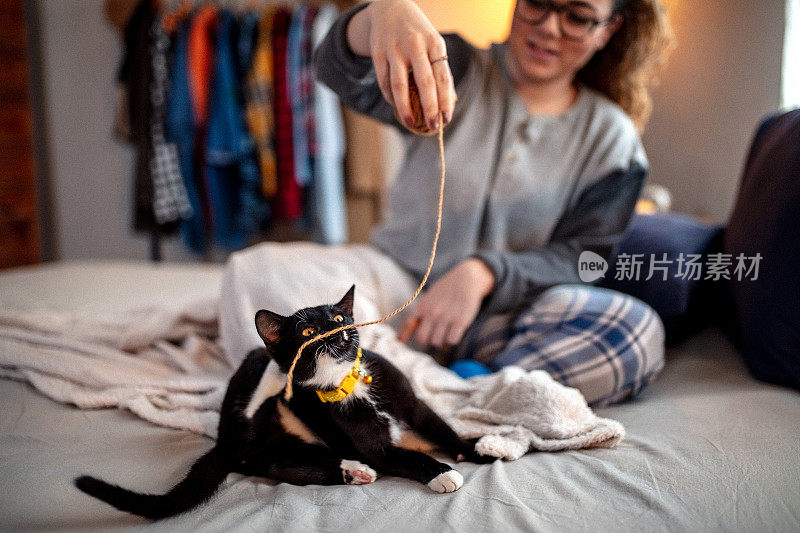 一个年轻女子在床上和她的猫玩