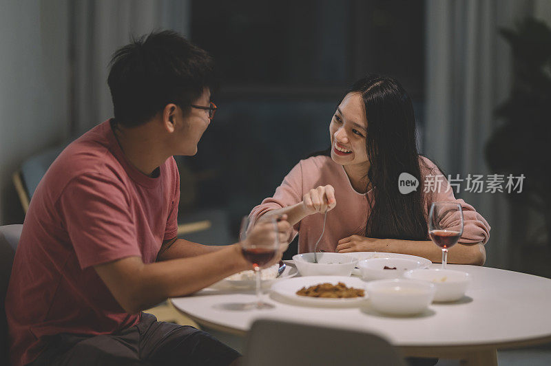 周末，一对亚洲华人夫妇在家里用红酒和中国菜共进晚餐