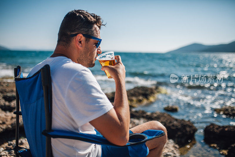 在海滩上喝啤酒的男人