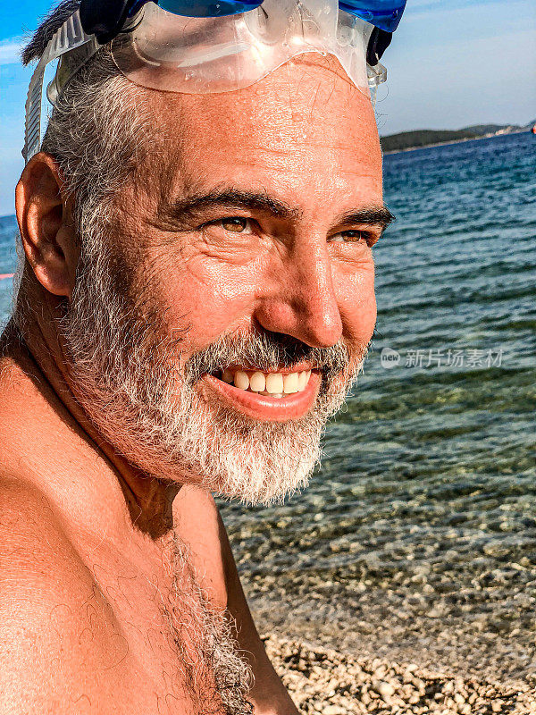 带着水肺面具微笑的成熟男人在暑假的海滩上享受