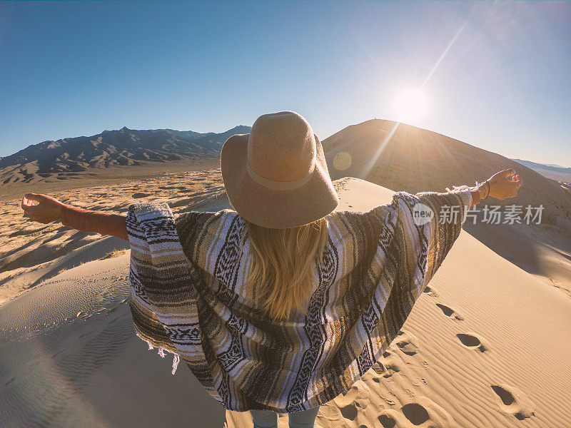 站在沙丘上的女人，伸开双臂，享受大自然的自由;女孩在山顶张开双臂徒步旅行