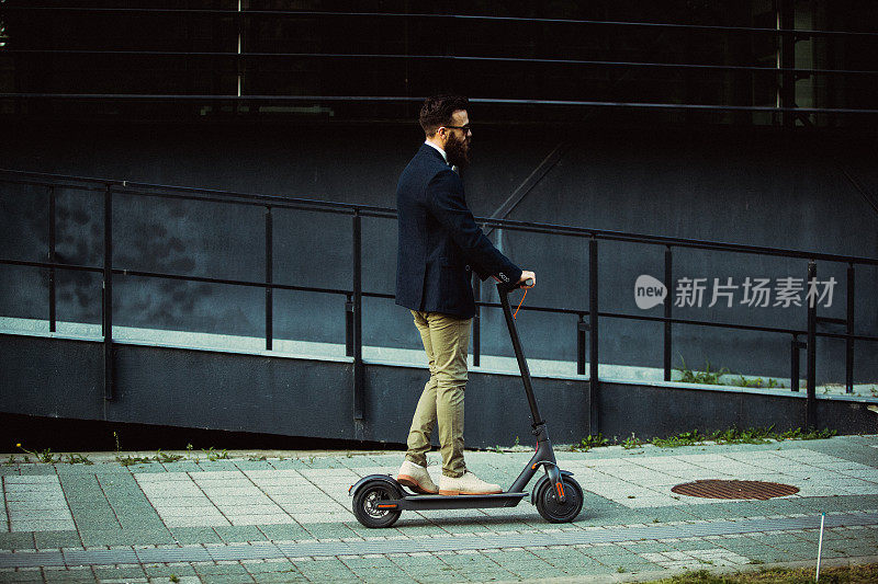 赶时髦的商人在城市里骑着滑板车