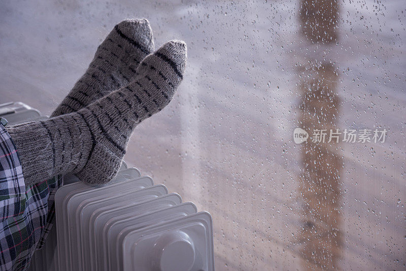 近距离图像的女人的脚散热器加热器在雨季的冬天。